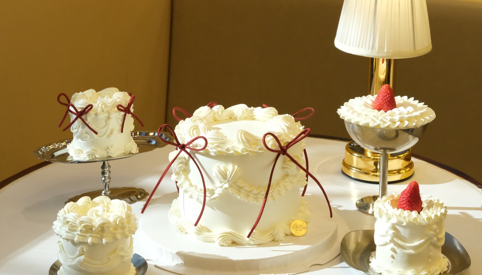 Cream cakes with red bows and strawberries at The Cake by Dav