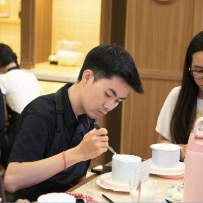 Student piping details onto a cake